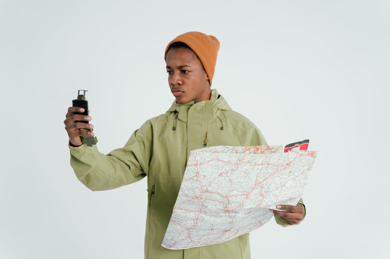 Portrait of a young man navigating with a map and a device, expressing adventure and exploration.